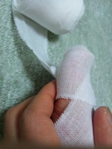 足の指先を覆う包帯の巻き方-指の腹側で折り、指先の方に包帯を持っていきます。