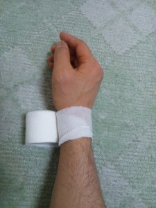手の親指の包帯の巻き方-はみ出した部分を折り込みます。